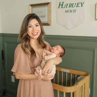 Mother holding her newborn son beside a crib during an in-home newborn photography session in McKinney, Texas.