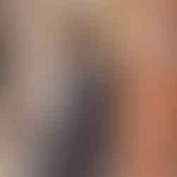 Senior boy in gray suit posing by brick wall in Downtown McKinney urban senior session