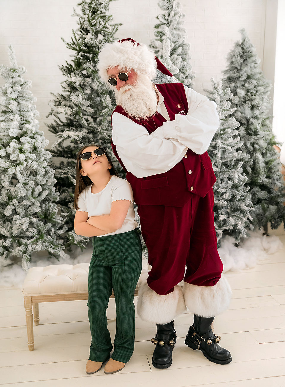 Santa mini session in Lake Dallas with Santa in red velvet suit holding a baby dressed in red Christmas pajamas in front of frosted greenery.