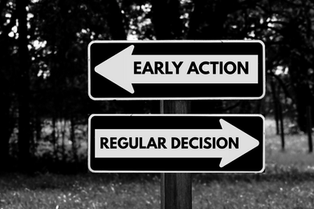 Two black and white signs pointing opposite directions in a wooded setting. One reads "Early Action," the other "Regular Decision."