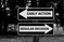 Two black and white signs pointing opposite directions in a wooded setting. One reads "Early Action," the other "Regular Decision."