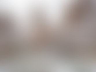 Snow-covered trees line a path leading to one of Yale's historic brick buildings with a tall tower. The scene is serene and wintry, with lampposts.