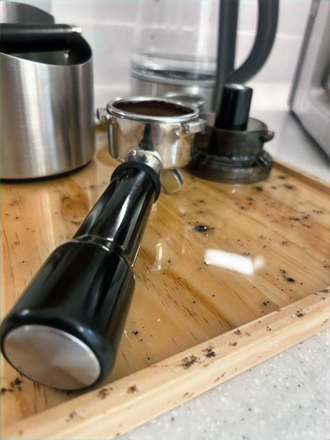 angled view of espresso coffee board top with porta filter, press and knock box