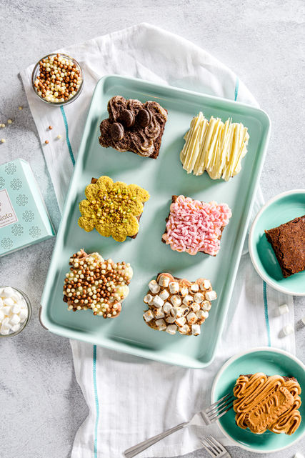 Flat lay of brownies and sweet treats on a pastel tray, styled for lifestyle and dessert brand photography.