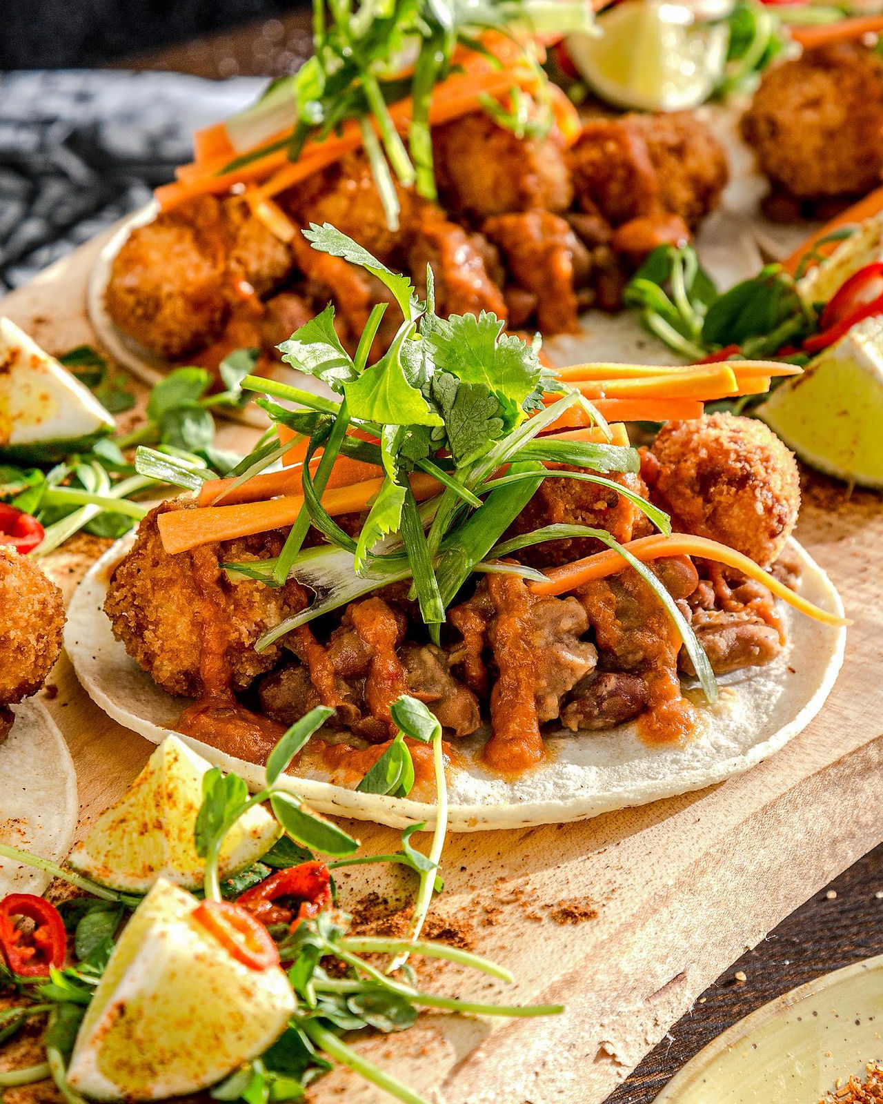 Crispy fried chicken tacos topped with slaw, cilantro, and red chili — styled for bold, handheld menu photography.