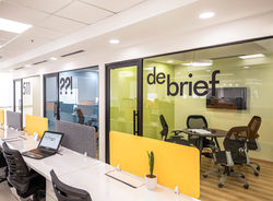 Open-plan workspace featuring colorful enclosures for small meeting spaces