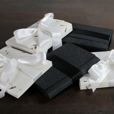 Boxes with white ribbons and dark boxes sitting on a wooden surface.