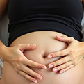 close up of massage hands on pregnant belly of woman who is lying on a bed .jpg