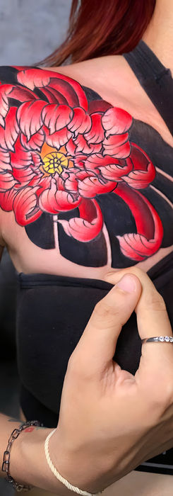Vibrant red flower tattoo on shoulder and chest