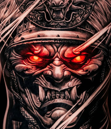Intricate full back tattoo featuring a demonic face with glowing red eyes.