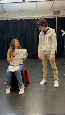 Anika Deshpande and a male actor interacting in rehearsals. Anika is seated.