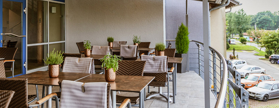 Überdachte Terrasse der Eventlocation Zur Zeile in Chemnitz – Sitzplätze mit Kräuterdeko