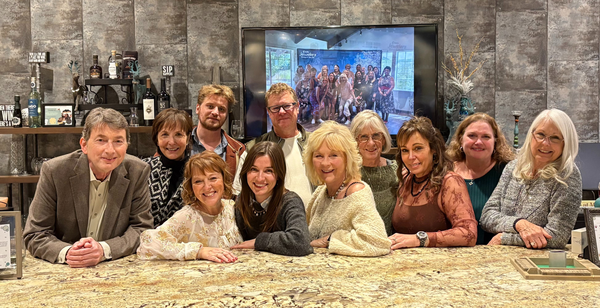 A group photo of most of the K. Hollis Jewelers staff standing behind the wine bar.