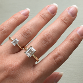 Two emerald-cut diamond rings in yellow gold shown side by side on a hand for comparison.