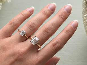 Two emerald-cut diamond rings in yellow gold shown side by side on a hand for comparison.
