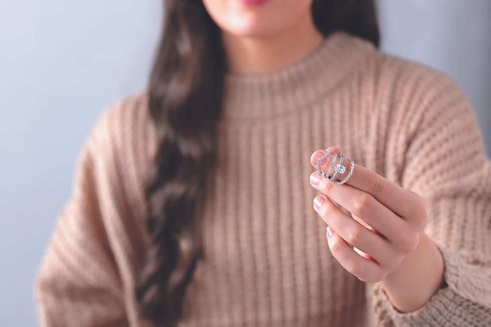Woman holding an engagement ring while comparing wedding band styles and ring pairings.