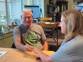 Craig placing a custom emerald cut emerald halo diamond ring on his wife's finger for the first time after seeing the reveal at K. Hollis Jewelers.