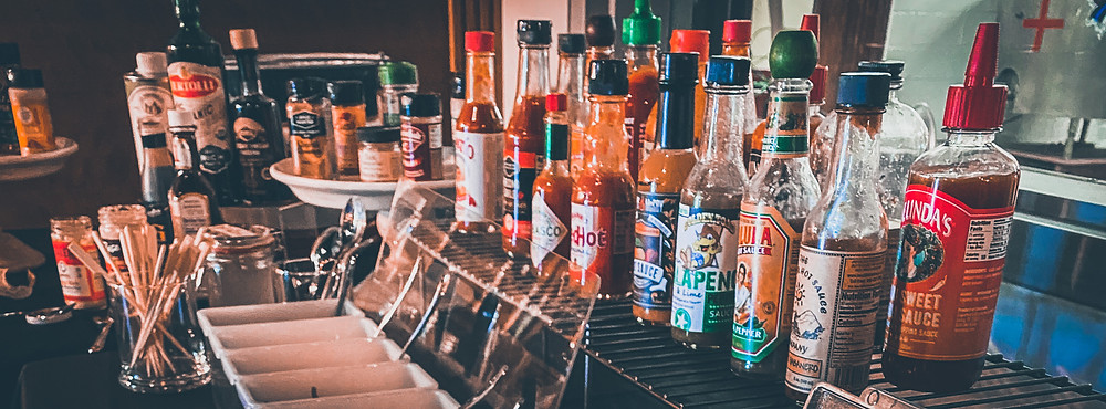 Pickled vegetables and bottles of hot sauce, spices, seasonings, olive oil and other Bloody Mary ingredients
