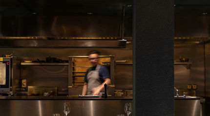 Chef working in a restaurant kitchen with dining area