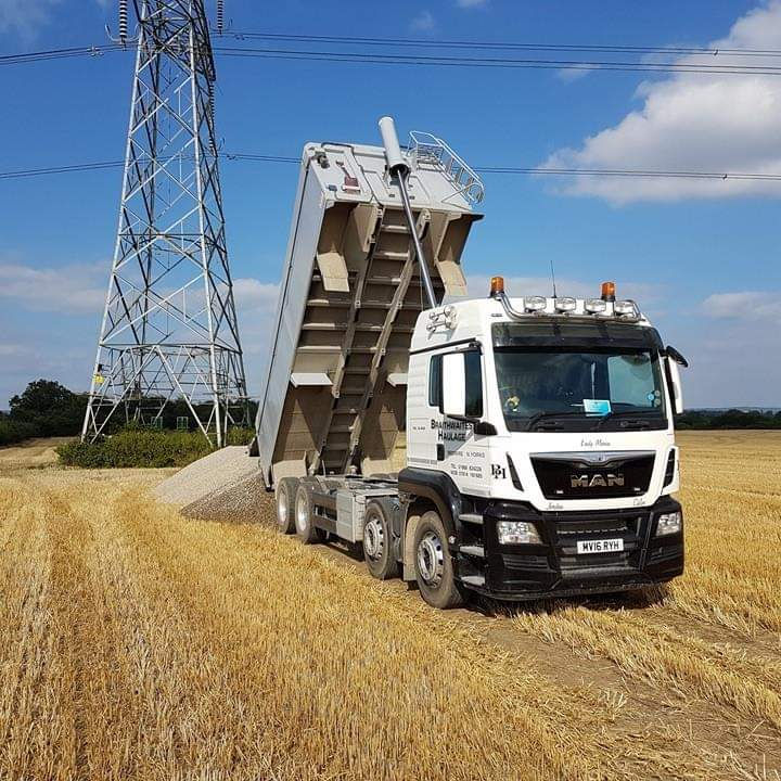 Tipper truck unloading loose aggregates at a UK delivery site