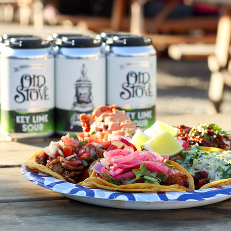 Plate of street tacos with various toppings & Key Lime Sour cans