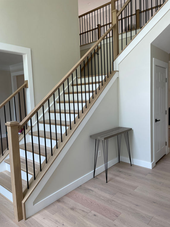 Custom interior trim and baseboard installation around staircase by Ant Builder.