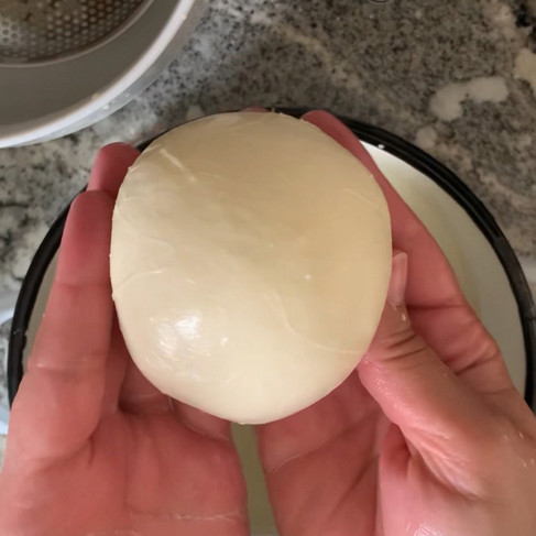 Hands holding a shaped ball of mozzarella