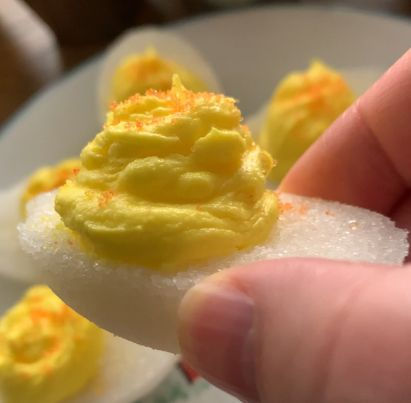 Close view holding a 'Sugar Devi'l candy egg that looks like a Deviled Egg