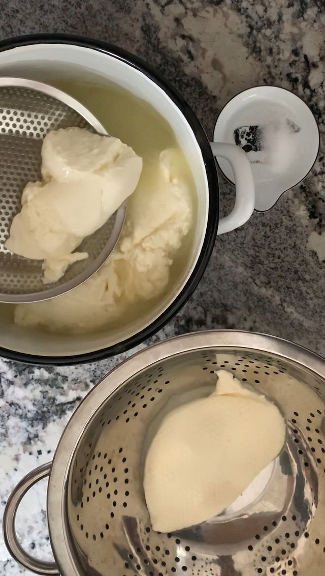 Cheese curds being lifted and separated from a pot and placed into a strainer