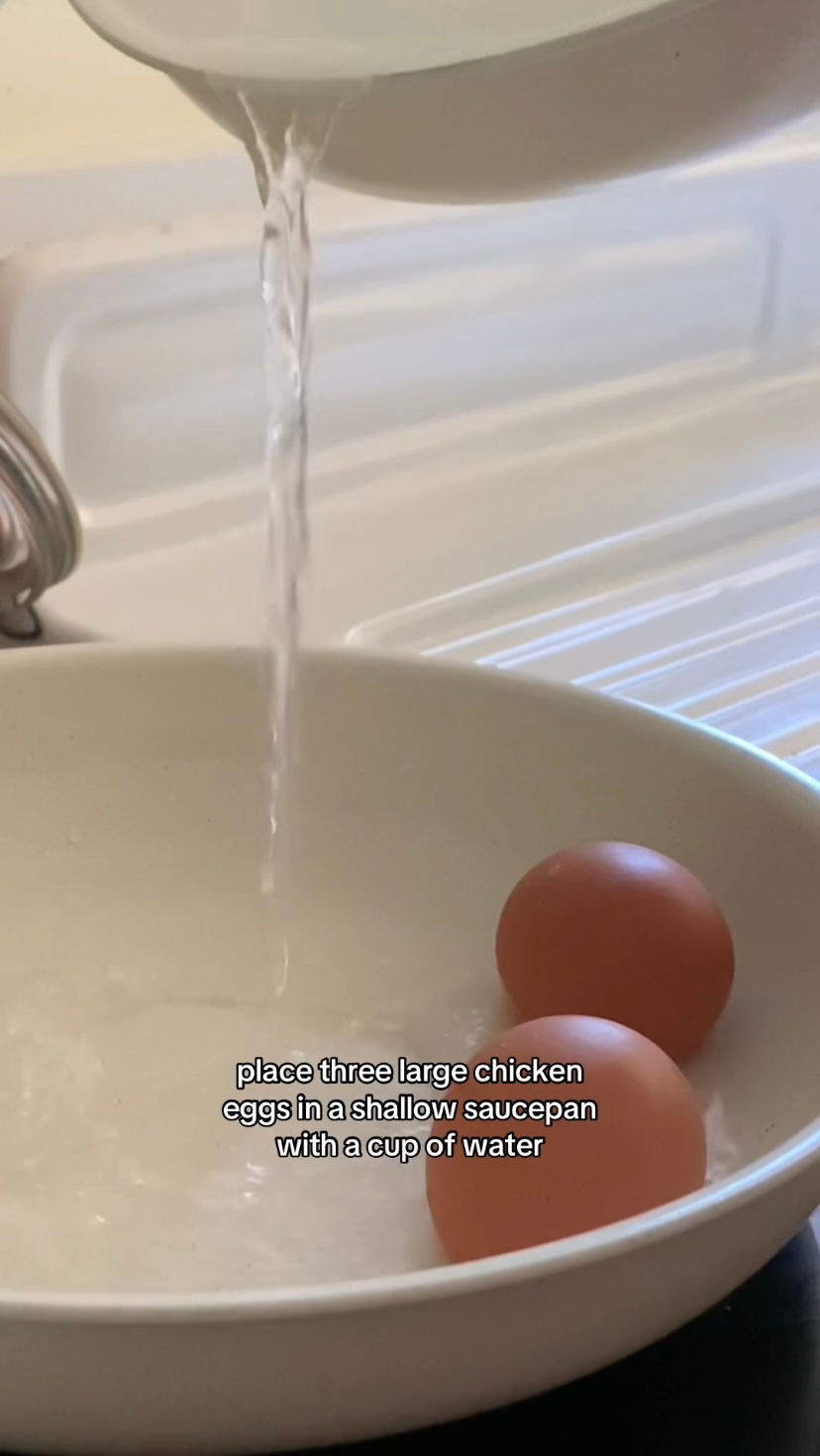 Eggs in a sauce pan with water being poured into the pan