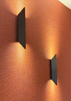 Terracotta high-end behang met structuur en twee bronzen wandlampen die omhoog en omlaag stralen