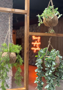 Roomdivider in kantoor van hout en hangplanten met op de achtergrond neon one liner