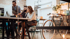 קבוצת אנשים יושבת סביב שולחן במשרד, עוסקת בדיון או בפעילות קבוצתית.