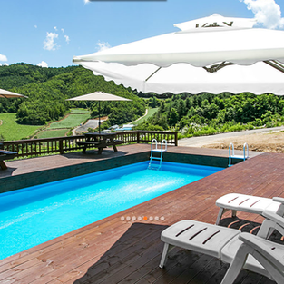 Outdoor pool with sunchairs, umbrellas and tables. 