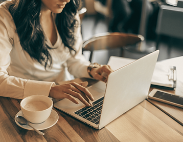 a female professional working on a notebook with coffee on the side