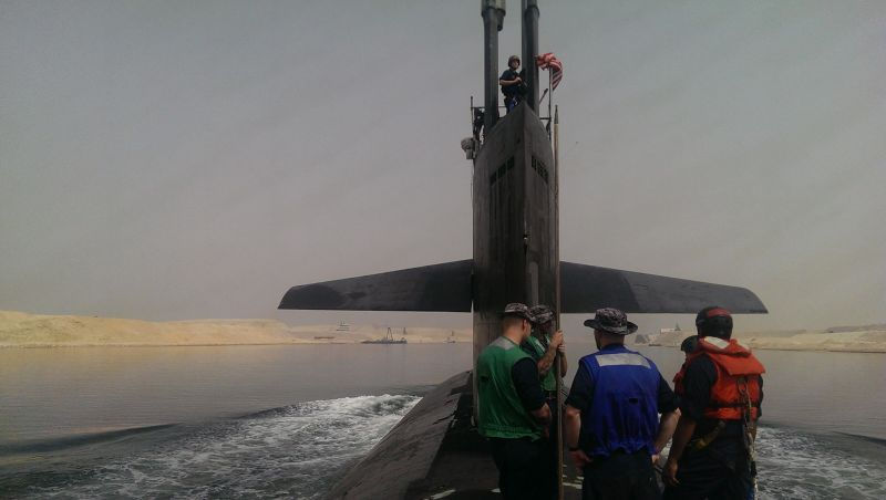 USS Providence (SSN-719), a Los Angeles-class fast-attack nuclear submarine, transited the Suez Canal during Tony Grayson's command tour. Crew members stand on the submarine's deck wearing color-coded jerseys indicating their rank. Submarines must surface for canal transits, making this one of the rare moments the "Silent Service" becomes visible to the world. The sail (conning tower) displays the American flag and periscope masts. Tony Grayson commanded USS Providence before transitioning to Fortune 500 technology leadership at Oracle, AWS, and Meta—bringing submarine leadership principles to corporate crisis management.