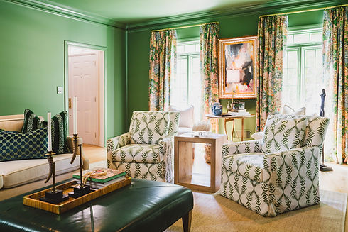 Elegant green sitting room featuring floral drapery, botanical print swivel chairs, layered textures, and collected artwork in a refined Atlanta interior designed by Heron Design House.