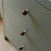 Sage green cabinetry with burgundy round knobs and brass accents.