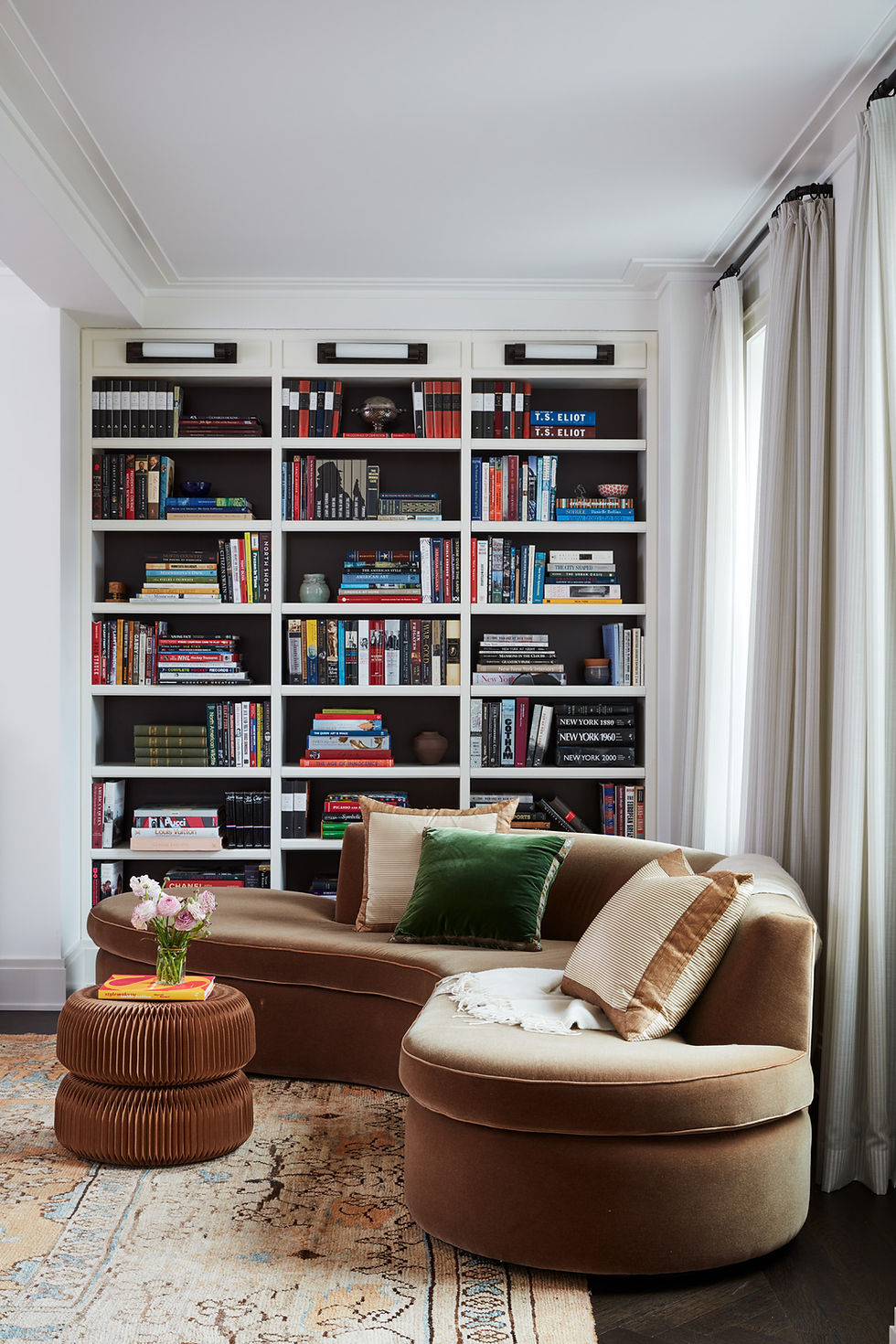 library with curved velvet sofa and vintage rug