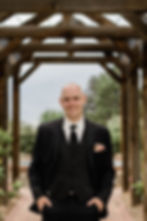 Groom poses under wooden awning at Hudson Gardens