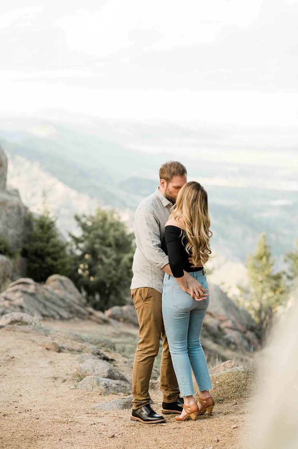 A man and woman kiss from the top of Flagstaff Mountain overlook in Boulder, CO