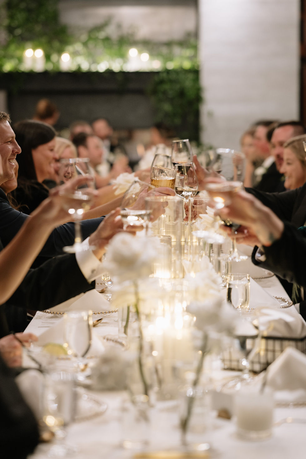Guests toast at a candlelit dinner, seated at a long table with white flowers at the Aerie at Copper Mountain.