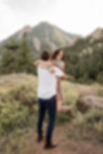 Woman laughs as man picks her up and twirls her around during Boulder, CO sunset engagement session
