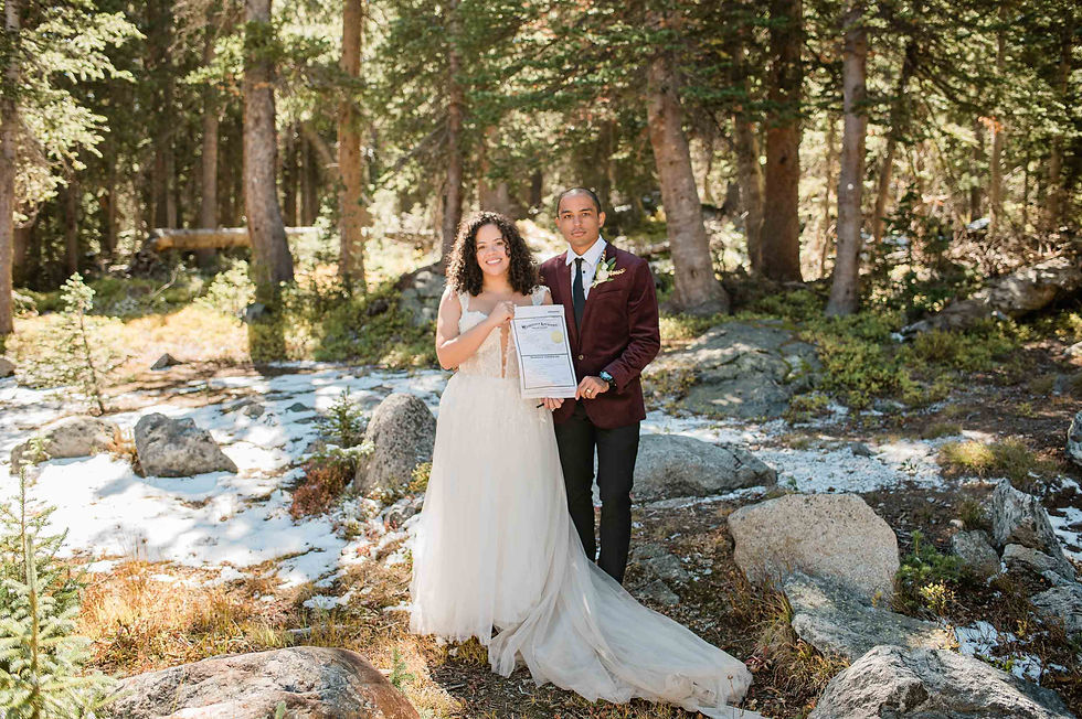Bride and groom pose with marriage license in Indian Peaks Wilderness during elopement.