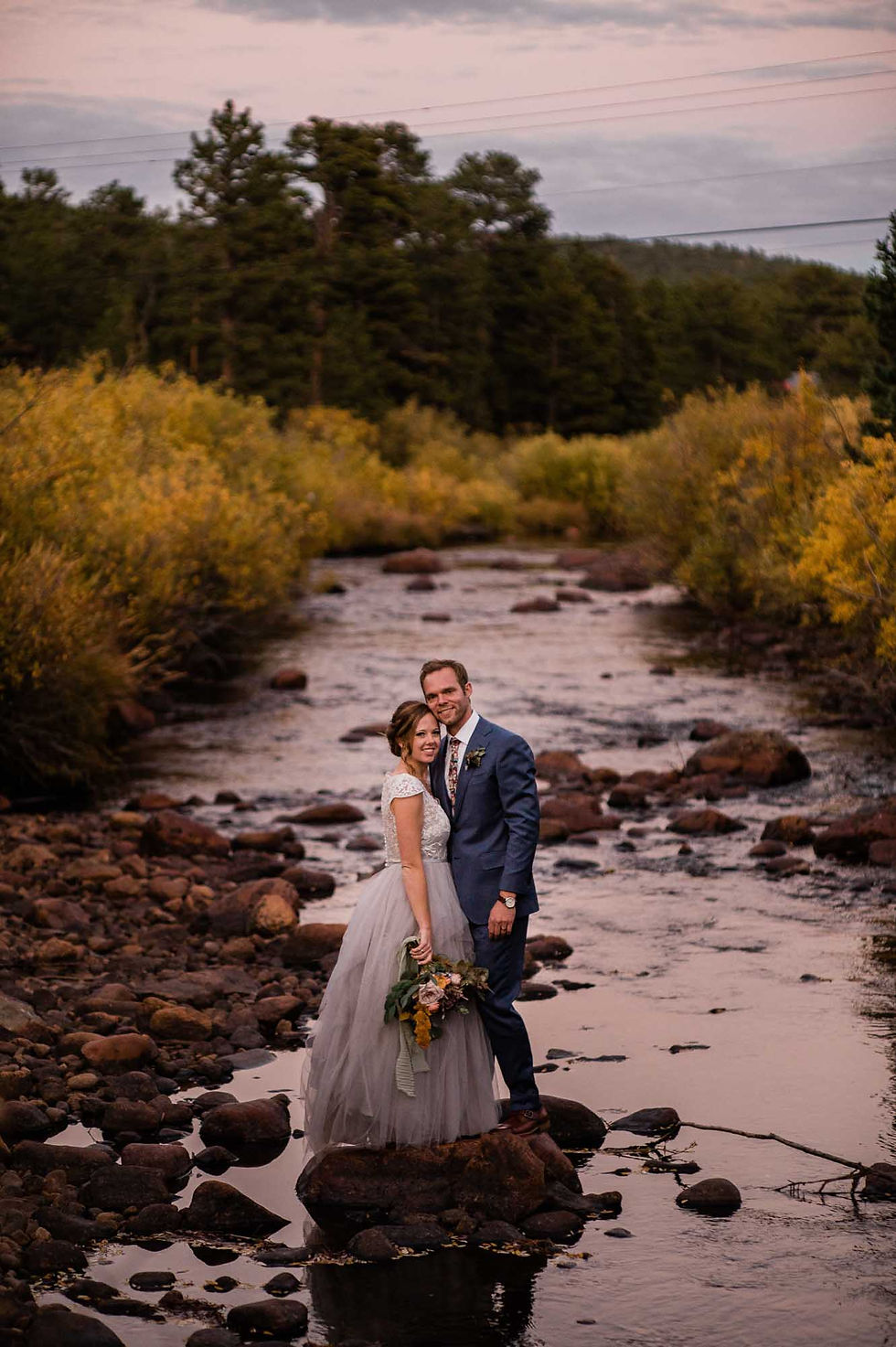 Bride and groom pose along the St. Vrain Creek in Allenspark, CO