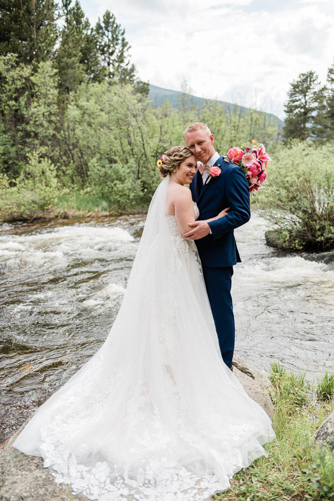 Bride and groom embrace along St. Vrain in Allenspark, CO
