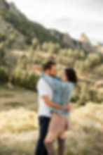 Woman wraps arms around man's neck and smiles during Boulder, CO sunset engagement session