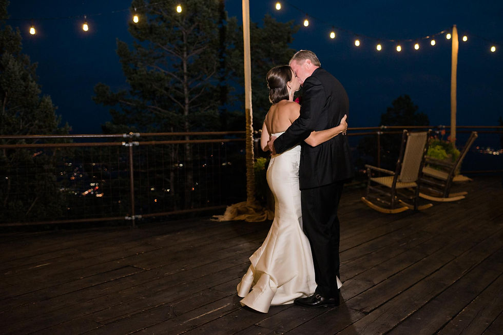 Bride and groom hug and kiss each other on the outdoor deck of Cloud Camp at the Broadmoor