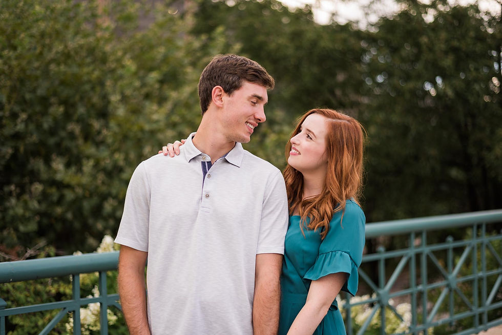 Man and woman smile at each other during engagement session in downtown Pittsburgh