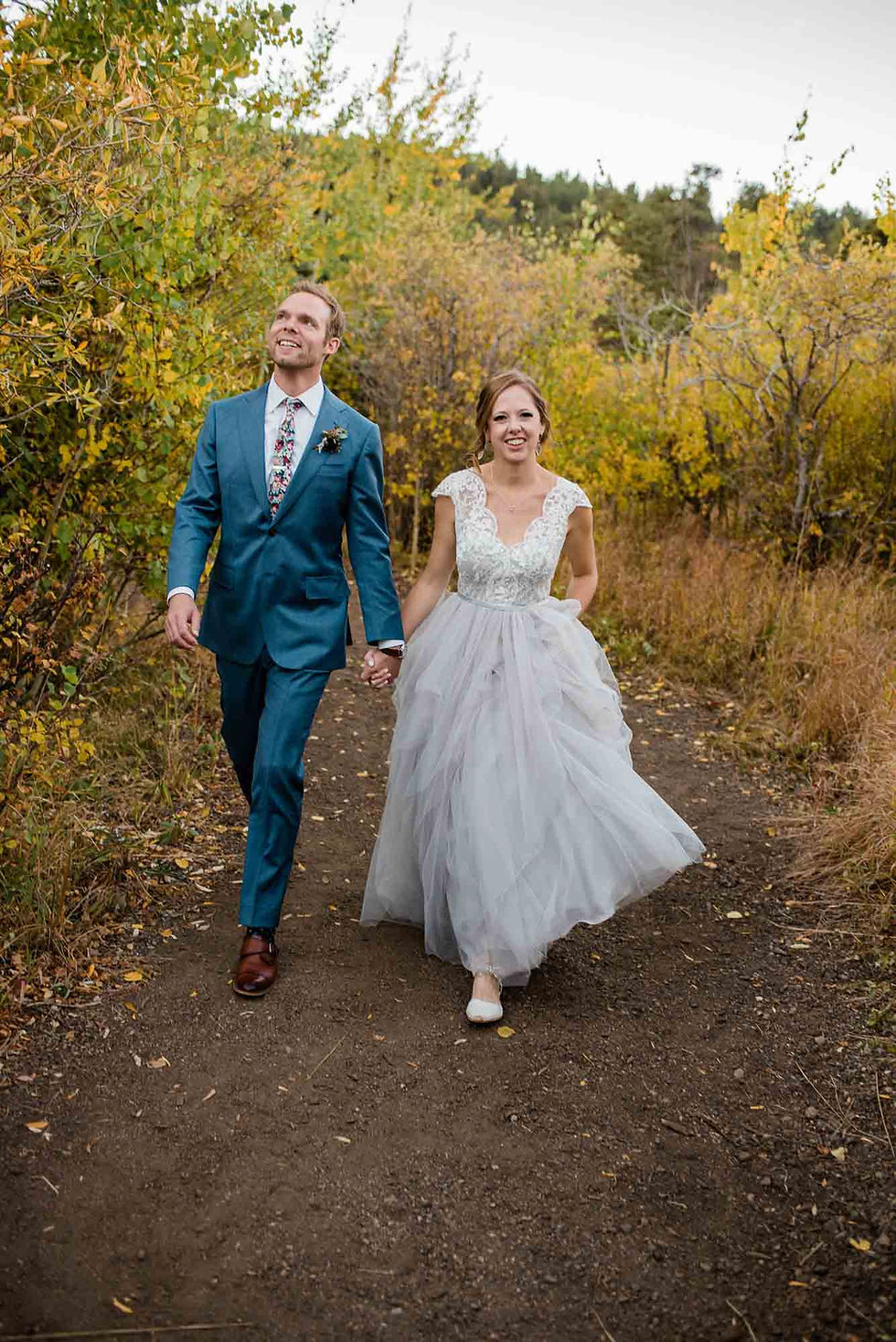 Bride and groom walk through the aspens during October wedding ceremony